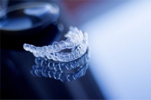 Two Invisalign aligners resting on reflective surface