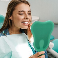 Dental patient using mirror to admire her dental implant restorations