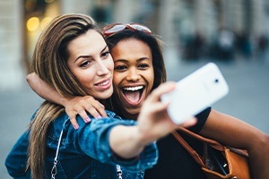 Two women with beautiful smiles after all ceramic dental restorations