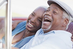 Man and woman laughing together after all ceramic dental restorations