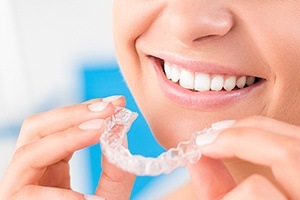 closeup of patient placing an Invisalign clear aligner tray