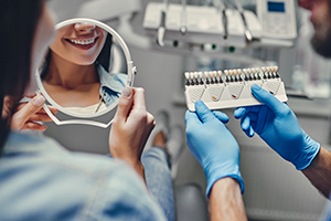 Patient looking at smile in mirror compared with porcelain veneer shade chart