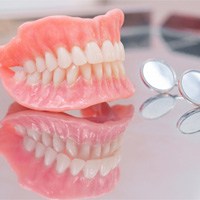 Full set of upper and lower dentures sitting on reflective table