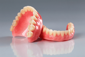 Full set of dentures in Bloomfield arranged on top of reflective surface