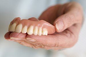 Hand holding a full denture