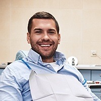 Man smiling in dental chair after chipped tooth repair