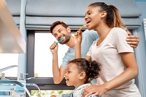 Family of three brushing teeth to prevent dental emergencies