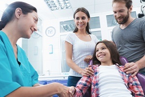 Parents and child talking to dental team member during family dentistry visit