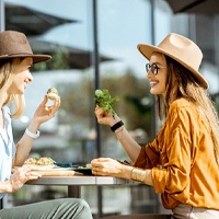 Friends eating a meal, enjoying benefits of dental implants in Bloomfield