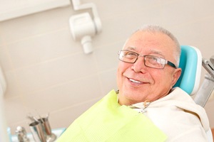 Happy senior dental patient at appointment for implant dentures