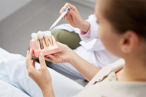 Dentist and patient looking at dental implant model