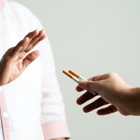 Person rejecting cigarettes to protect blood clots after oral surgery