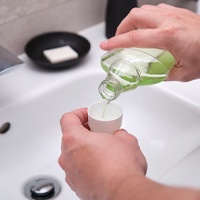 Man pouring mouthwash into cap as part of oral hygiene routine