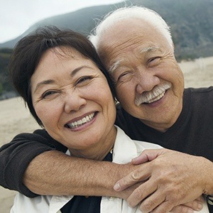 Man and woman smiling together after single tooth dental implants treatment