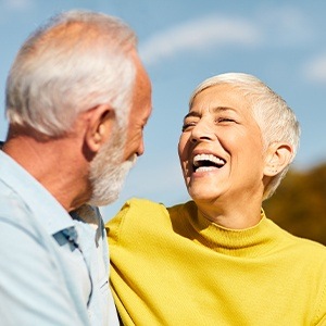 Man and woman smiling after dental implant tooth replacement