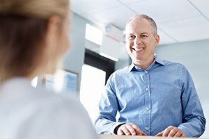 Man discussing cost of dental implants with dental team member