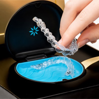 Hand placing Invisalign aligners back in storage case