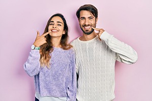 Happy couple pointing at their teeth