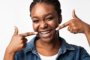 Teen girl pointing to smile with traditional braces