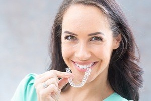 Woman holding up her Invsialign clear aligner