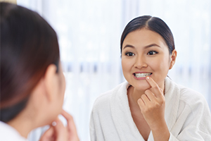 Woman with gum disease looking at her smile in the mirror