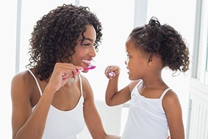 Mother and daughter brushing teeth together