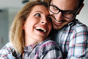 Man and woman with flawless smiles after porcelain veneer treatment