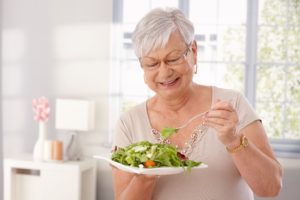 Older woman with dentures enjoying a tasty salad
