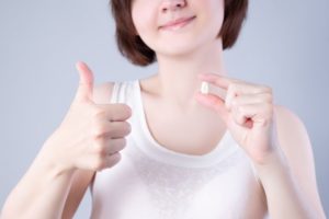 Woman holding extracted tooth, giving thumbs up