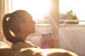 Woman on sofa, enjoying morning cup of coffee