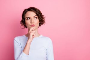 Thinking woman standing against pink background