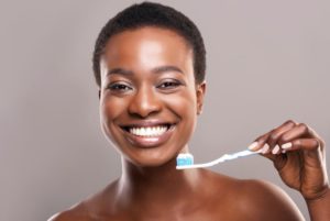 Woman with beautiful smile holding toothbrush and toothpaste