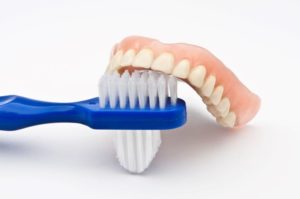 Denture with brush against white background