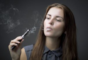 Woman smoking e-cigarette against neutral background