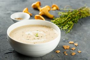 Bowl of creamy soup in front of soup ingredients